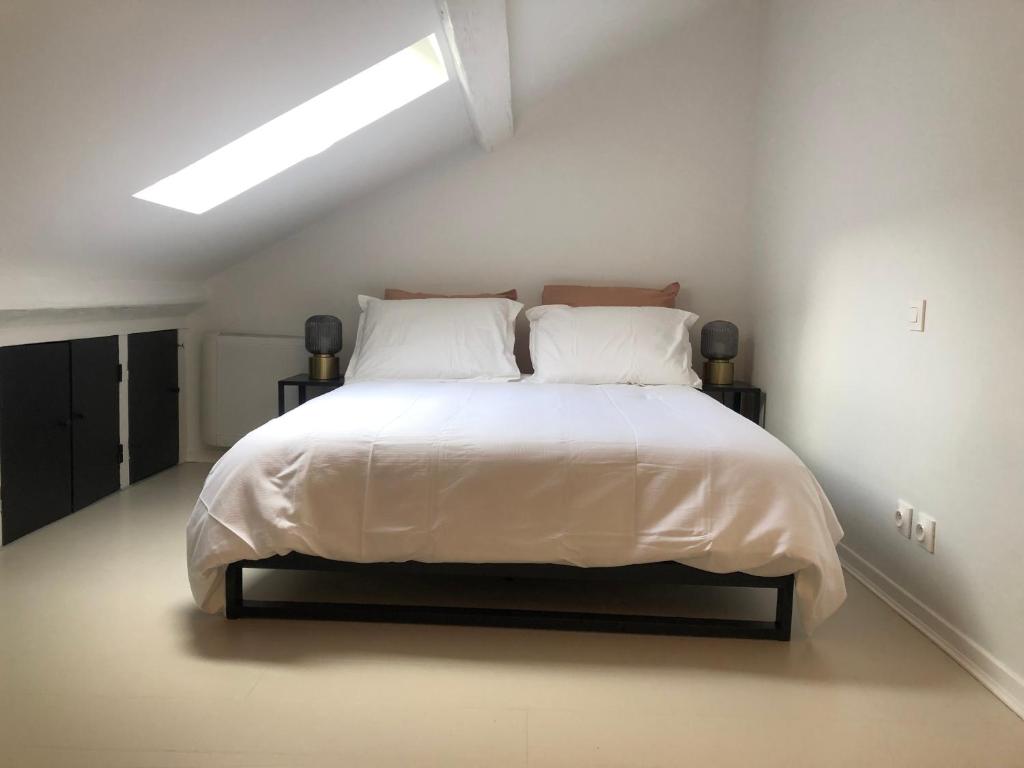 a bedroom with a bed with white sheets and pillows at Joli duplex in Dijon
