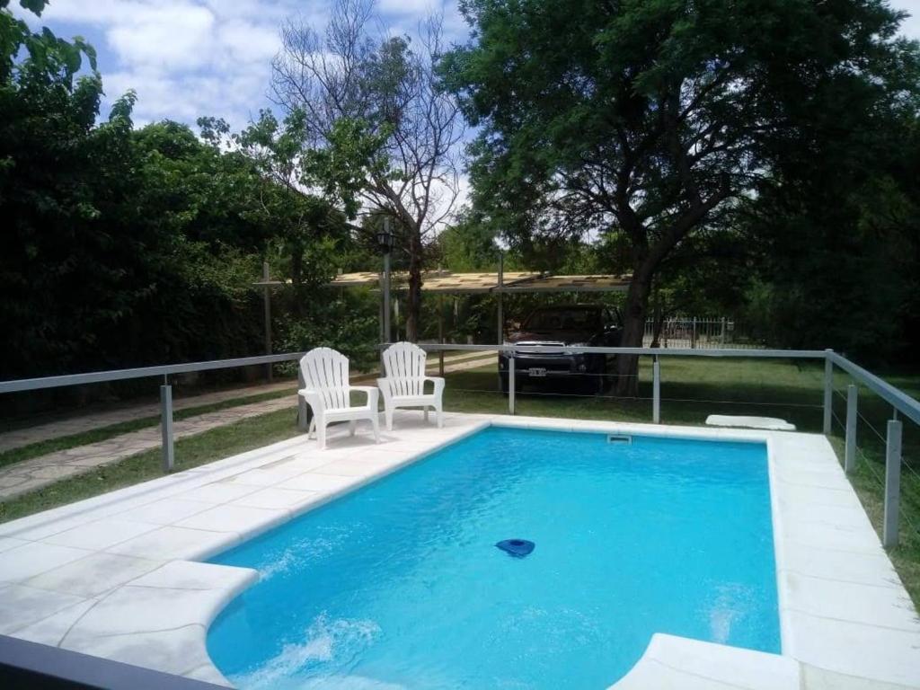 una piscina con 2 sillas blancas al lado en El Chinchero en Merlo