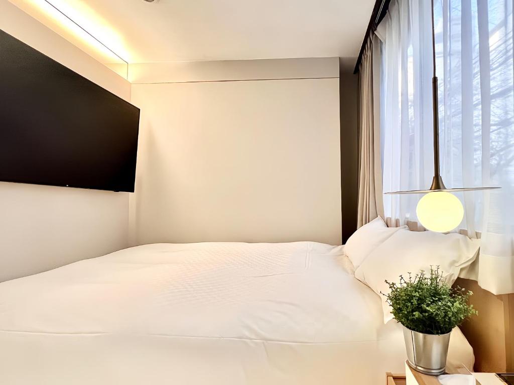 1 dormitorio con cama blanca y ventana en 东京上野超级中心 设计师房间Ybob 上野公园3分钟 车站1分钟 超级繁华 免费wifi 戴森吹风 en Tokio