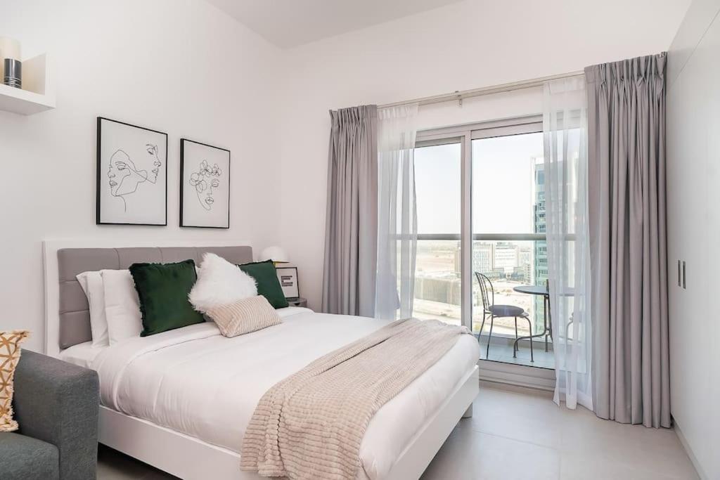 - une chambre blanche avec un lit et une grande fenêtre dans l'établissement HiGuests - Bella Rose Studio With Stunning Desert Views, à Dubaï