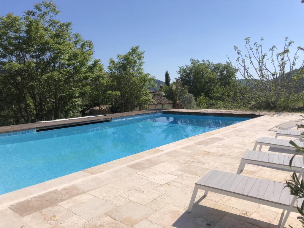 une piscine avec des chaises et des arbres en arrière-plan dans l'établissement Villa Cabasse, à Cabasse
