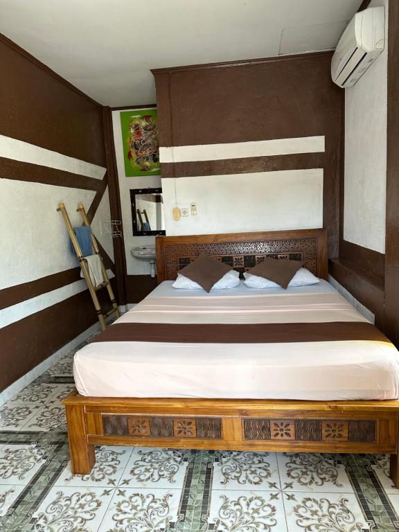 a bedroom with a bed with a wooden headboard at Cozy Alfia Inn in Gili Trawangan