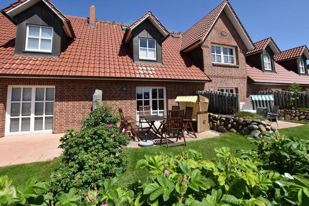 a brick house with a table and chairs in the yard at Norderstr 32, Kite Hüs in Westerland