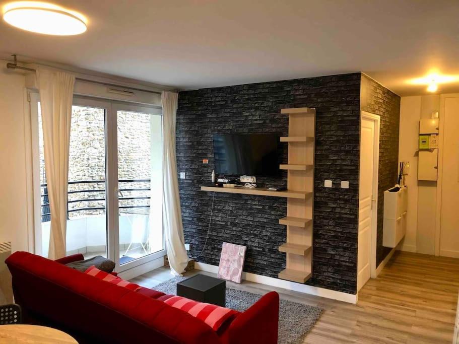 ein Wohnzimmer mit einem roten Sofa und einer Ziegelwand in der Unterkunft Flat in Choisy Le Roy, 6 min from Paris in Choisy-le-Roi
