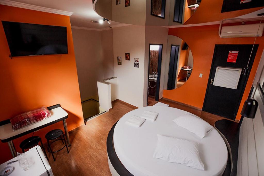 a small room with a white bed and a table at MOTEL MK 66 in Mairinque