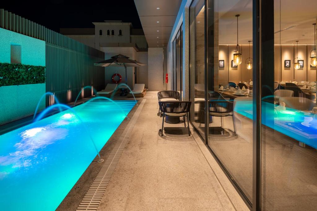 a hotel swimming pool with chairs and a table at Boudl Al Rawdah in Buraydah