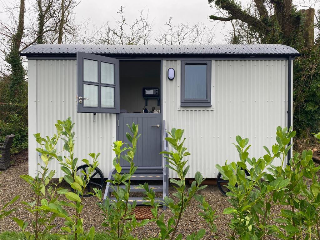 a small white shed with a grey door at Burren Garden Glamping Hut in Boston