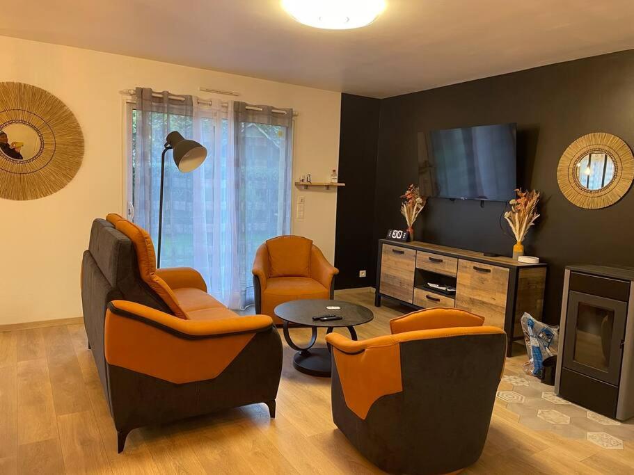 ein Wohnzimmer mit Stühlen, einem Tisch und einem TV in der Unterkunft La Montbourgeoise in Montebourg