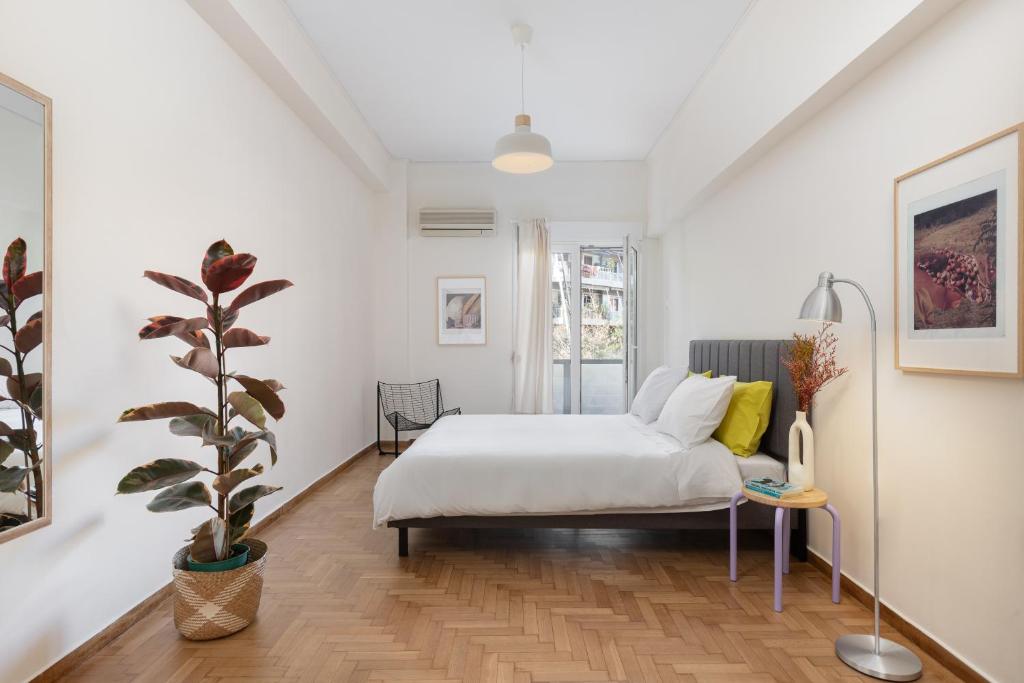 a white bedroom with a bed and a potted plant at Lovely Apartment in Exarcheia in Athens
