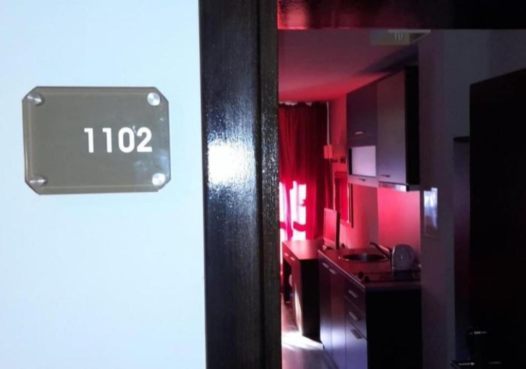 een keuken met rode verlichting en een klok op de deur bij Igzila apartment in Banya