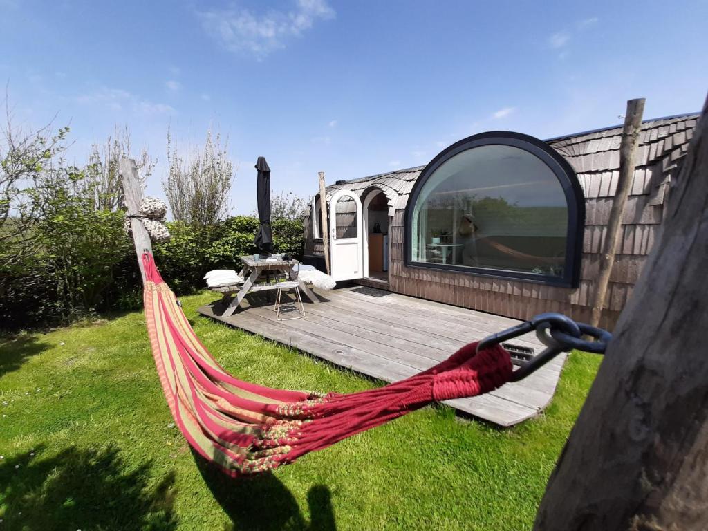 een hangmat in een tuin naast een hut bij Tiny House De Boet, in Natuurgebied en vlakbij het Strand in Callantsoog