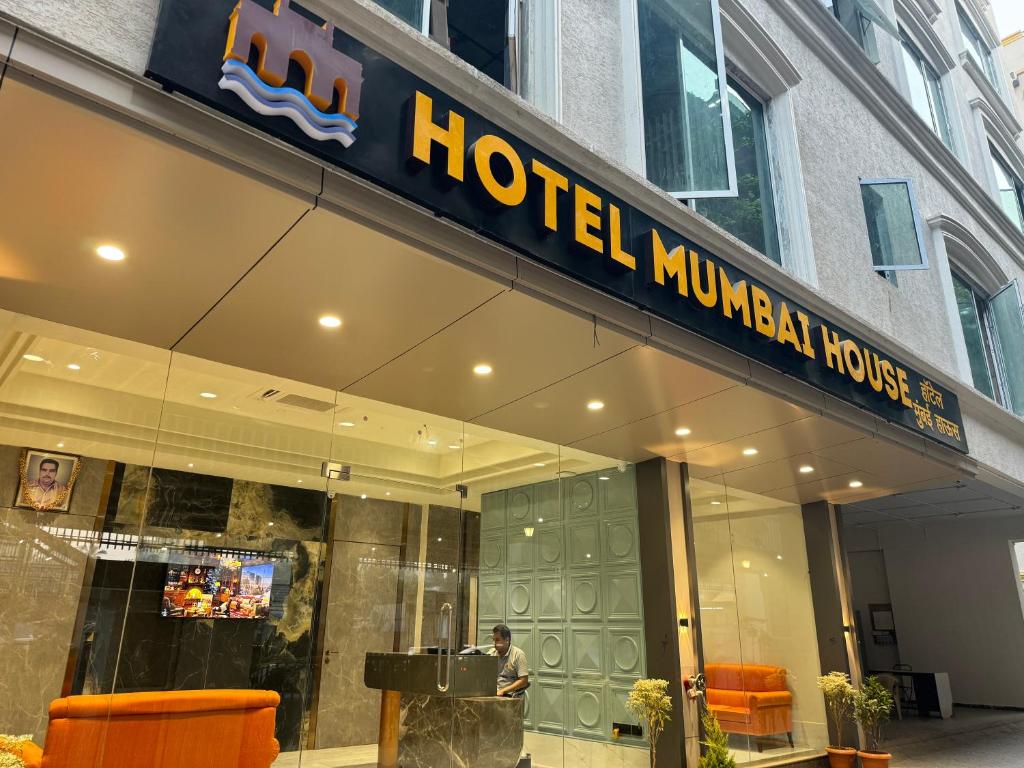 un vestíbulo de hotel con un hombre de pie fuera de un edificio en Hotel Mumbai House, Malad en Bombay