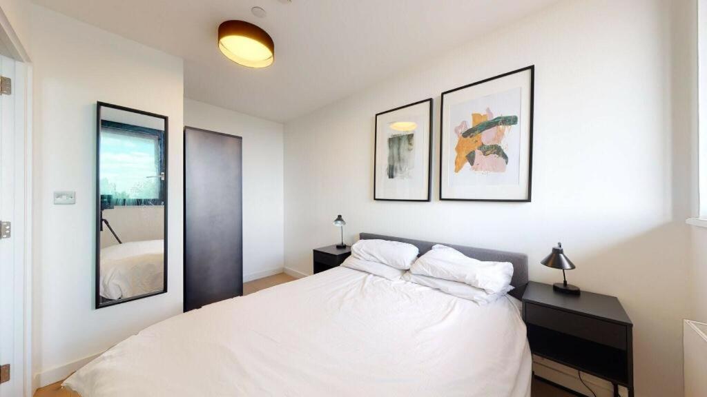 ein Schlafzimmer mit einem weißen Bett und zwei Bildern an der Wand in der Unterkunft 迪諾文旅 in Hsia-shih-pi
