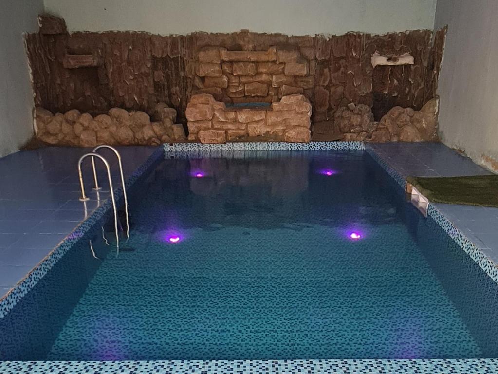 una gran piscina con luces moradas. en Al Fannan Farm - Family House, en Ras al Khaimah