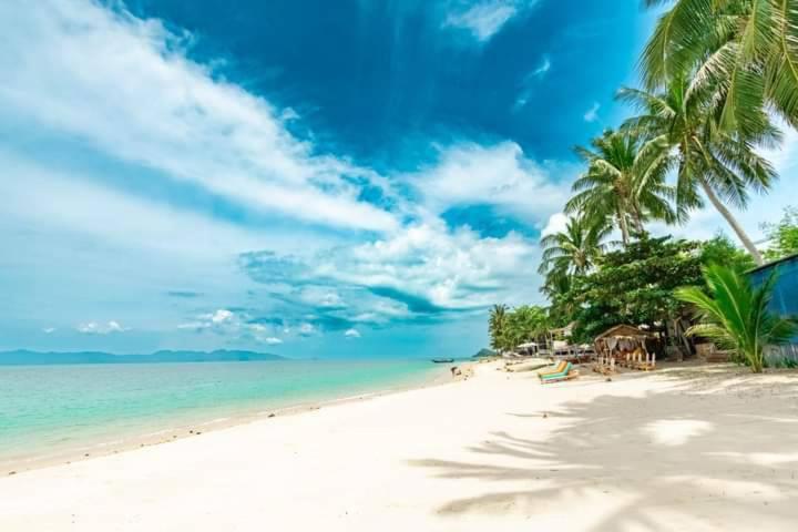 uma praia arenosa com palmeiras e o oceano em BangPo Resort em Ban Bang Po