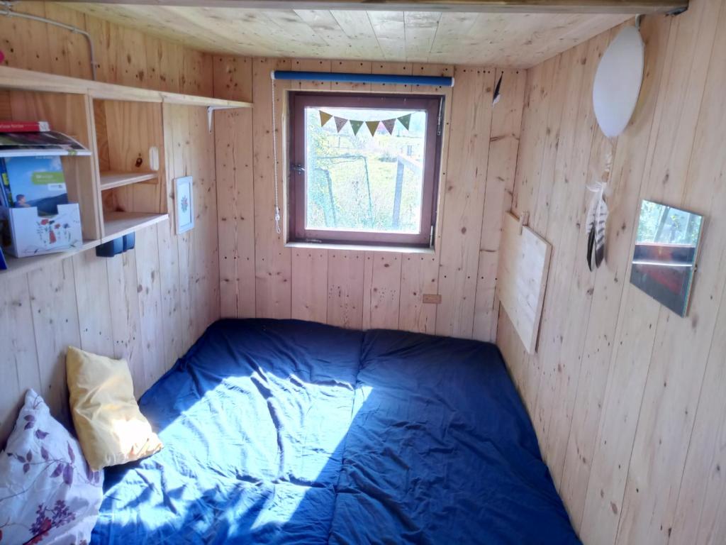ein Schlafzimmer mit einem blauen Bett in einem Holzzimmer in der Unterkunft Schäferwagen Hotzenplotz 