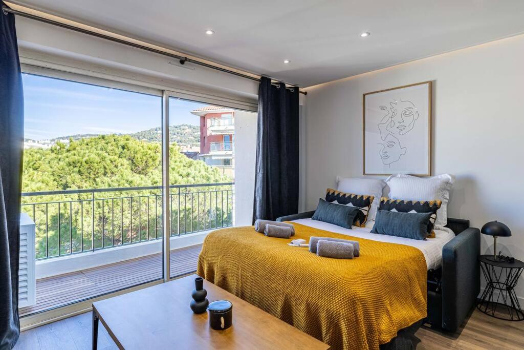 une chambre avec un lit et une grande fenêtre dans l'établissement 8 MERLE - Beau studio au centre de Cannes avec balcon !, à Cannes