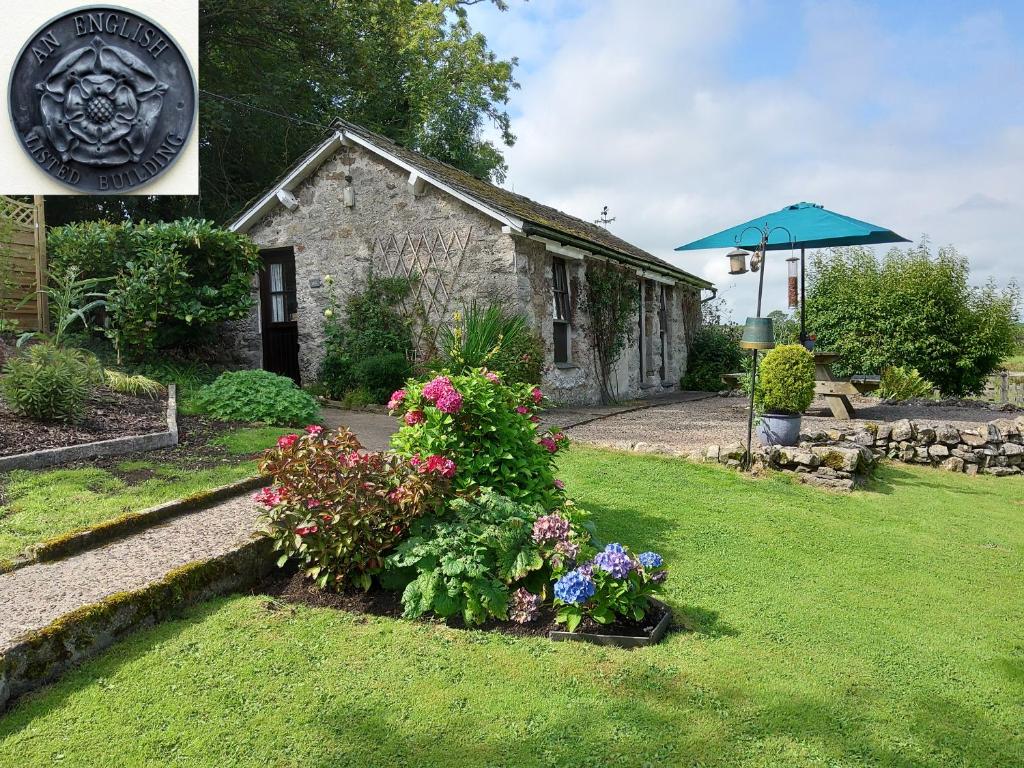 a garden with flowers in front of a building at Lile Cottage at Gleaston Water Mill in Ulverston