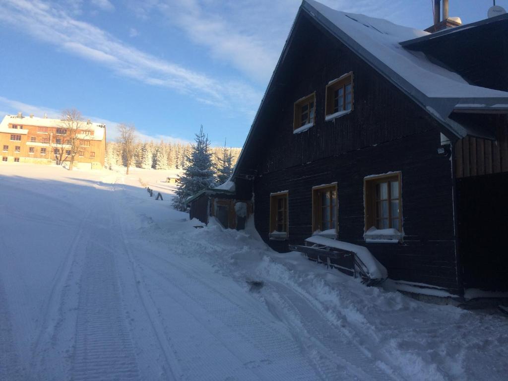 a house is covered in snow next to a street at chata Školička in Horni Misecky