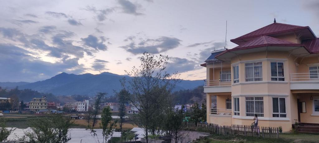a large house with mountains in the background at Indrayanifarms in Sundarijal