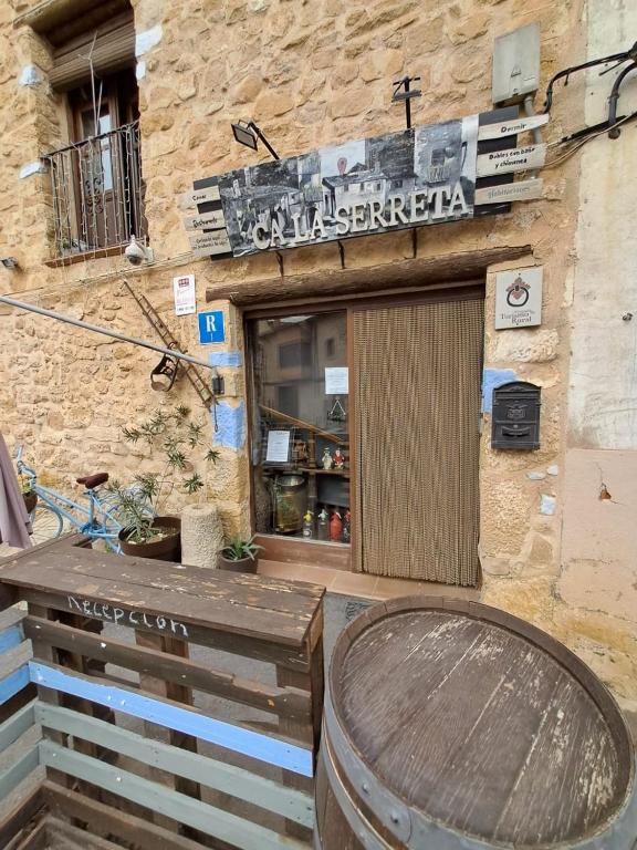 een gebouw met een tafel en een vat voor een winkel bij Ca la Serreta in Cretas
