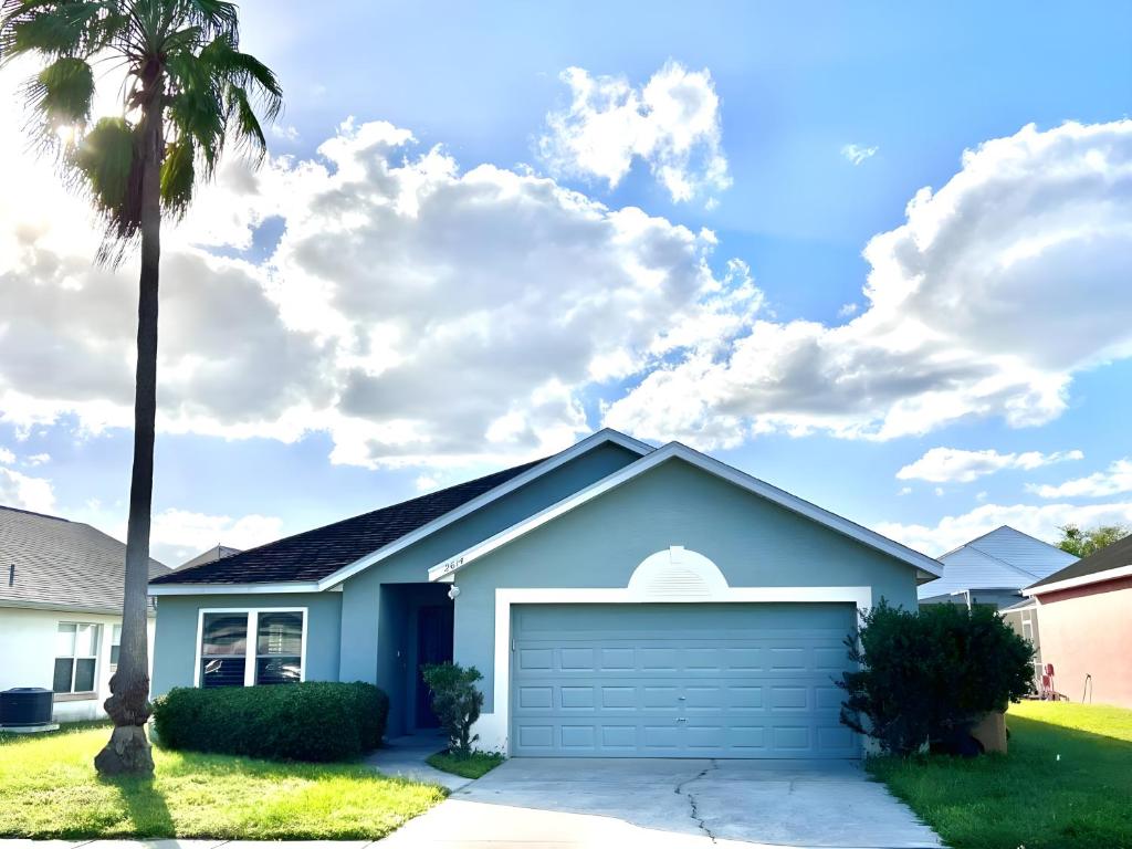 a house with a garage and a palm tree at Brittany - Perfect 3 BR Pool Home in Kissimmee