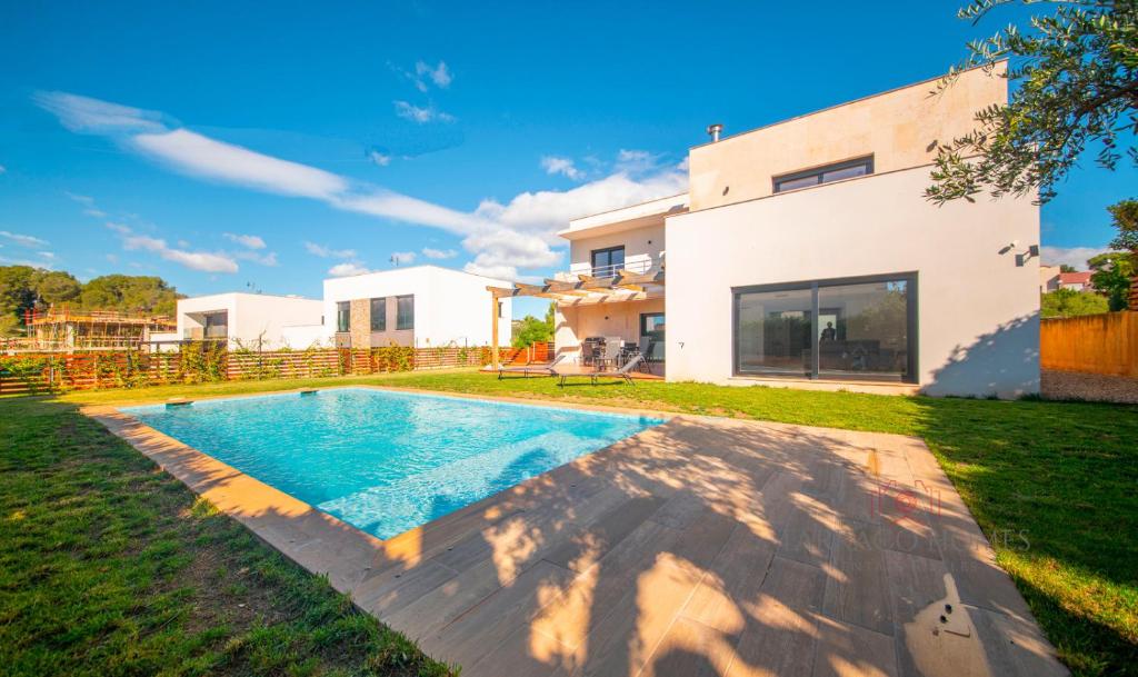 a villa with a swimming pool in front of a house at TarracoHomes - TH130 Casa Golf Costa Dorada in Catllar