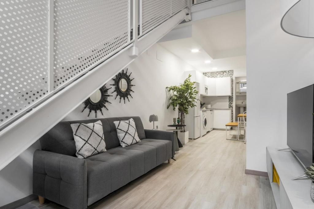 a living room with a couch under a staircase at Modern- 1 Bd 1,5 Bth- Delicias Atocha in Madrid