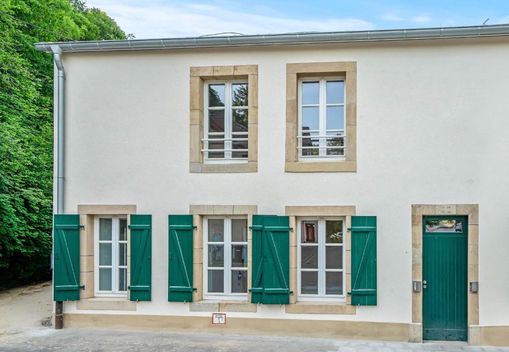a white house with green shutters at Maison Lasauvage in Differdange