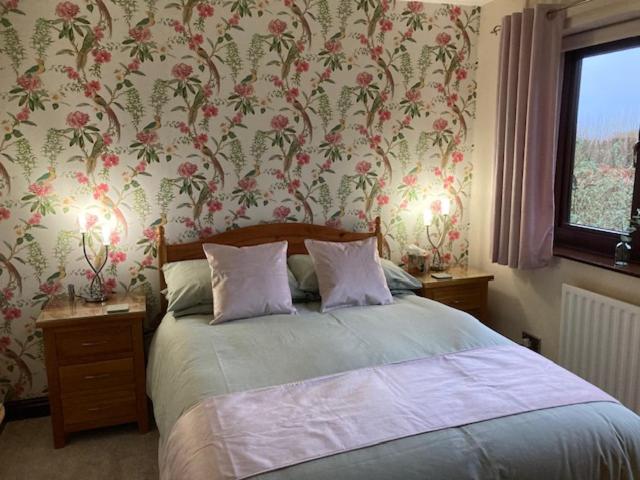 una camera da letto con un letto e carta da parati floreale di The Willows 