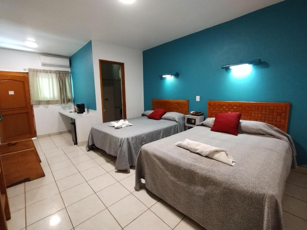 ein Schlafzimmer mit zwei Betten und einer blauen Wand in der Unterkunft Los Ciruelos Oaxaca in Oaxaca de Juárez