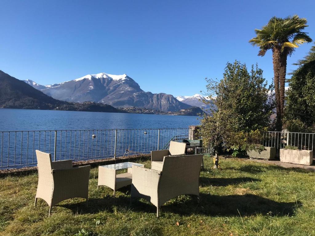 a group of chairs and a table next to a body of water at White Garden - Apartment with access to the Lake in Lierna