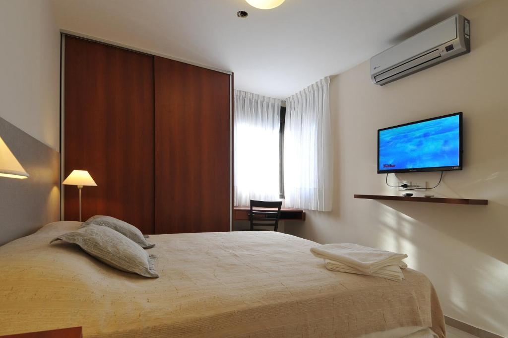 um quarto com uma cama e uma televisão de ecrã plano em AVIS Departamentos peatonal em Villa Carlos Paz