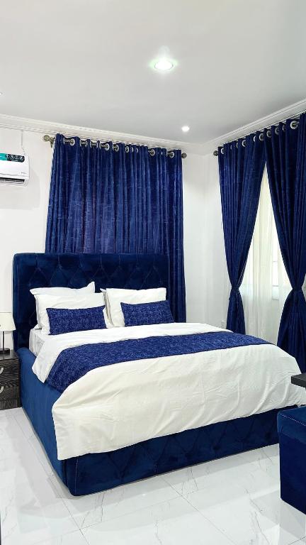 een blauw en wit bed in een slaapkamer met blauwe gordijnen bij Blueocean.cog in Benin City