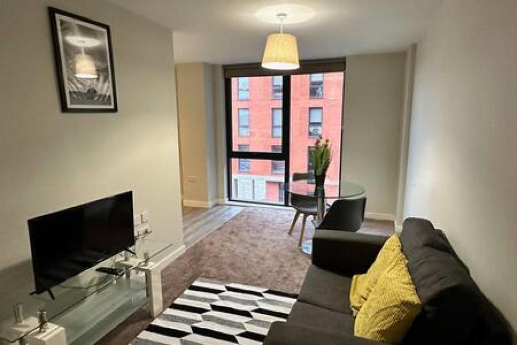 a living room with a couch and a television at Cosy 1 Bed Central Manchester Apartment Sleeps 2 in Manchester