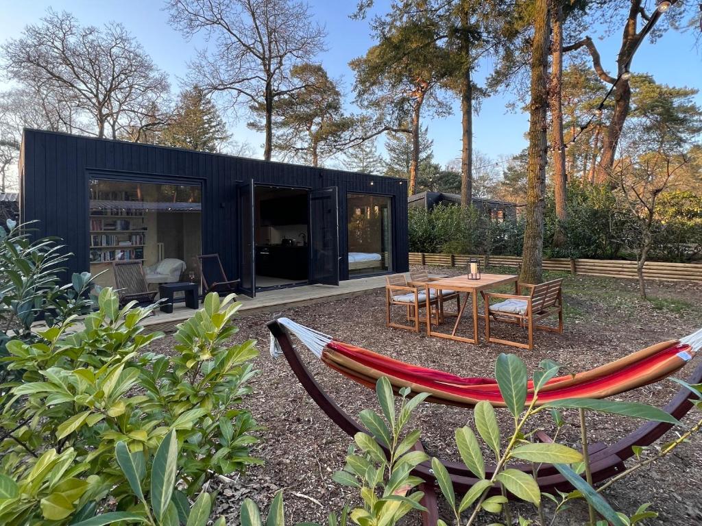 a black house with two hammocks in the yard at Taiga tiny house in Nunspeet
