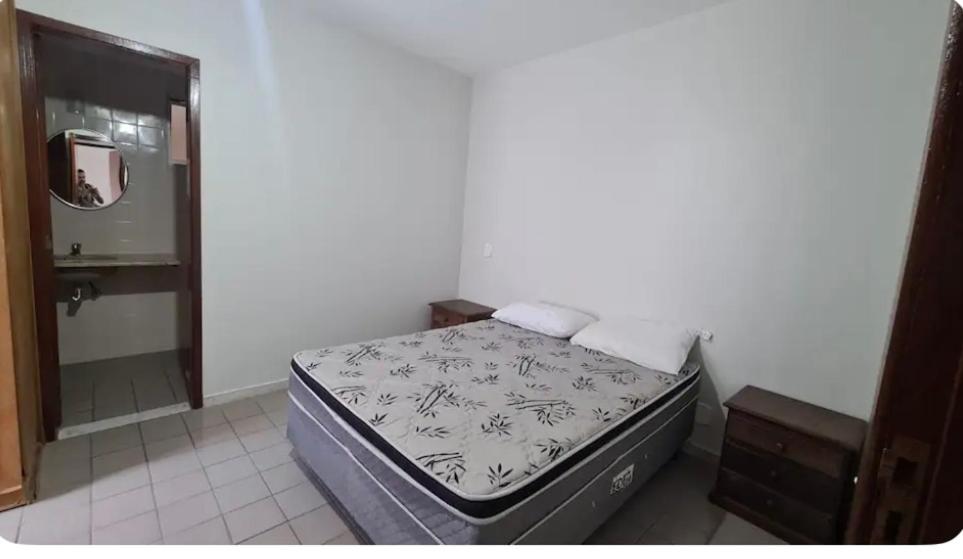 ein kleines Schlafzimmer mit einem Bett und einem Spiegel in der Unterkunft Condomínio Juacema in Cabo Frio