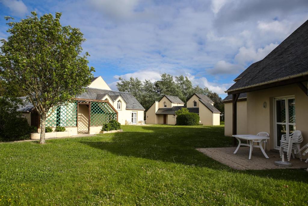 a yard with a house and a table and chairs at VVF Fouesnant les Glénan in Fouesnant
