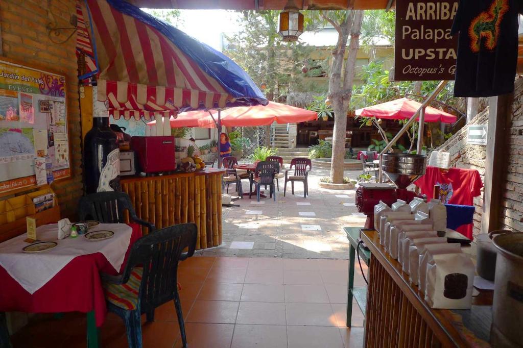 un ristorante con tavoli e ombrelloni su un patio di The Octopus's Garden Hostel a La Cruz de Huanacaxtle