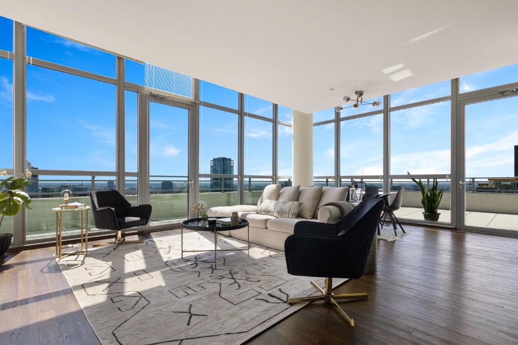 a living room with a couch and chairs and windows at Penthouses near Fulton Market-Cloud9-365 in Chicago