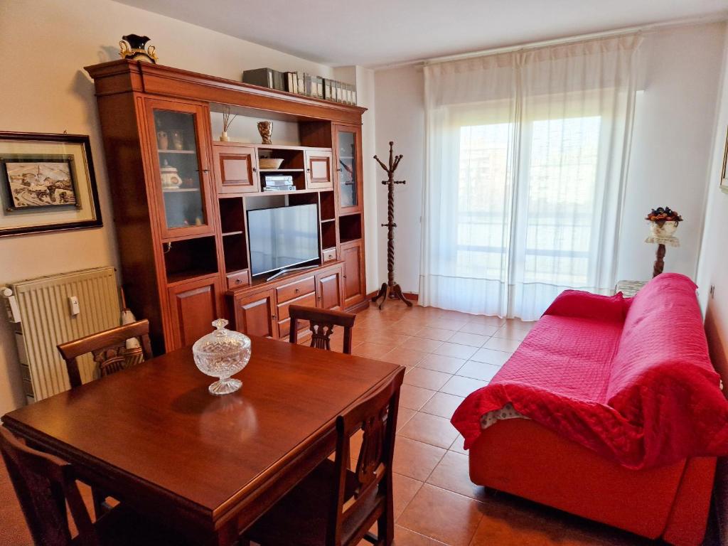 uma sala de estar com um sofá vermelho e uma mesa em DOMUS DIVI - Eur Torrino em Roma