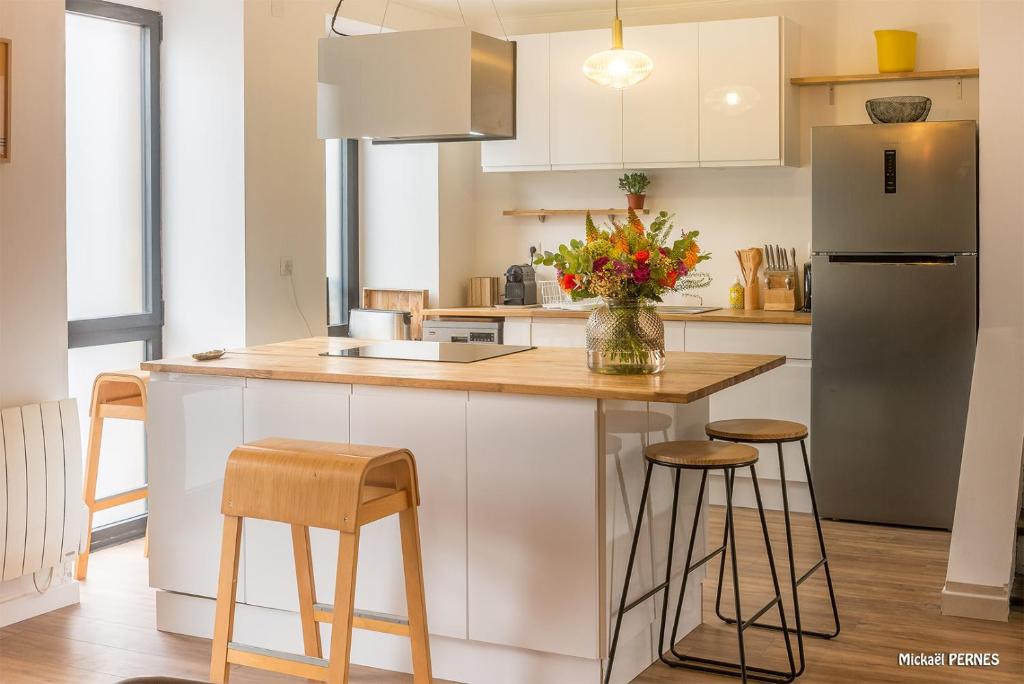 uma cozinha com um balcão com bancos e um frigorífico em RÉF 483 - LORIENT maison de ville avec terrasse jardinet em Lorient
