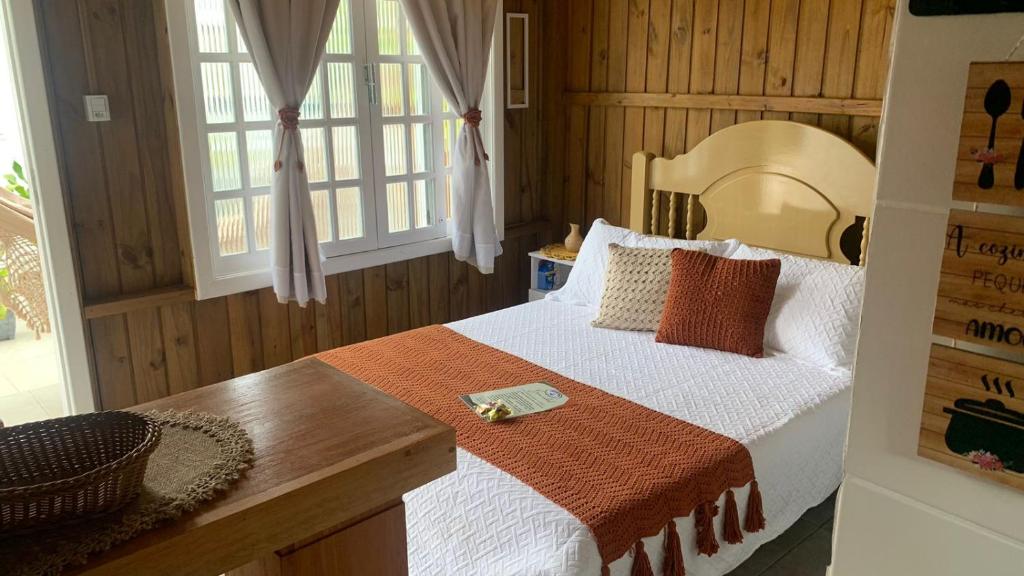 1 dormitorio con 1 cama grande y pared de madera en Cabanas MORIÁ en Garopaba