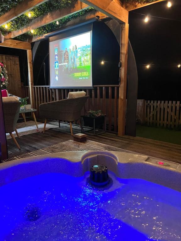 a tv and a jacuzzi tub in front of a screen at Horse Park Hideaway, Luxury Hot Tub Glamping Retreat in Pilling