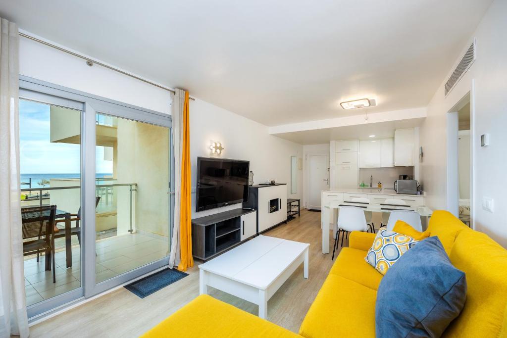 a living room with a yellow couch and a kitchen at Apartamento Olga in Cala Millor