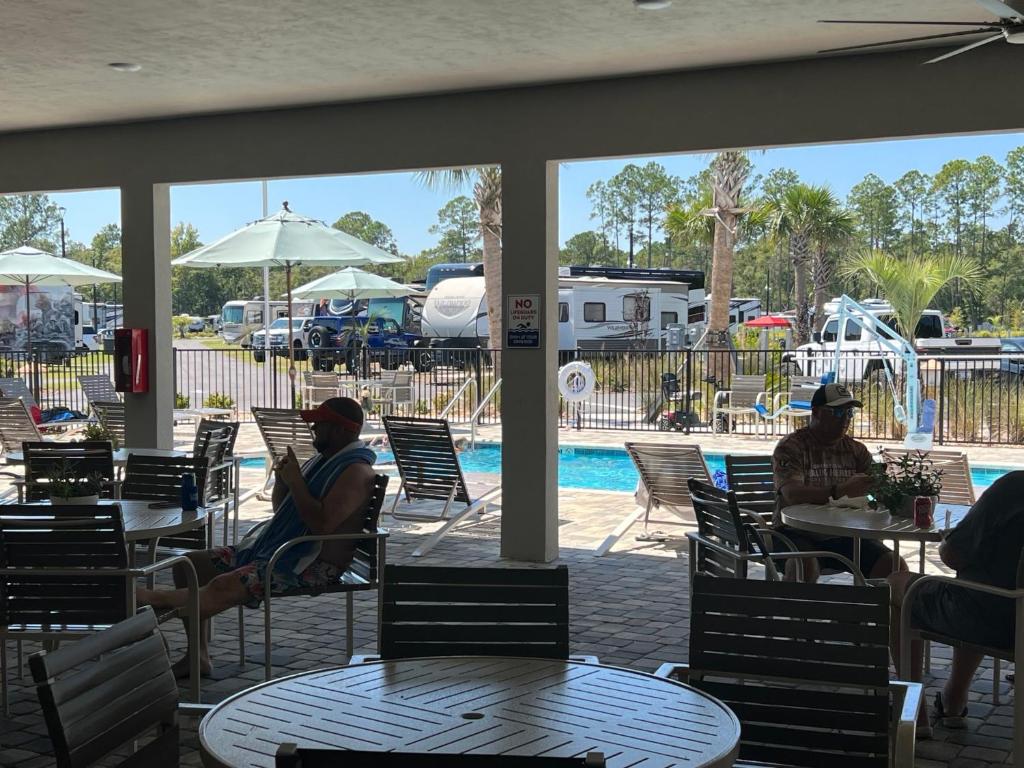 un grupo de personas sentadas en mesas cerca de una piscina en Santa Fe Palms RV Resort en Gainesville