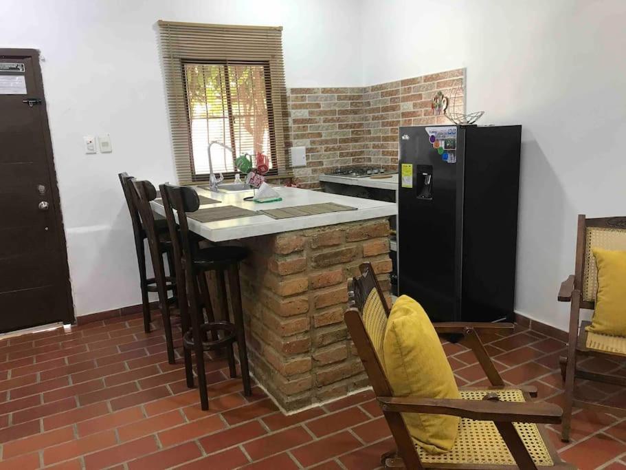 a kitchen with a counter with chairs and a refrigerator at Apartamento Concepción Mompox in Mompós
