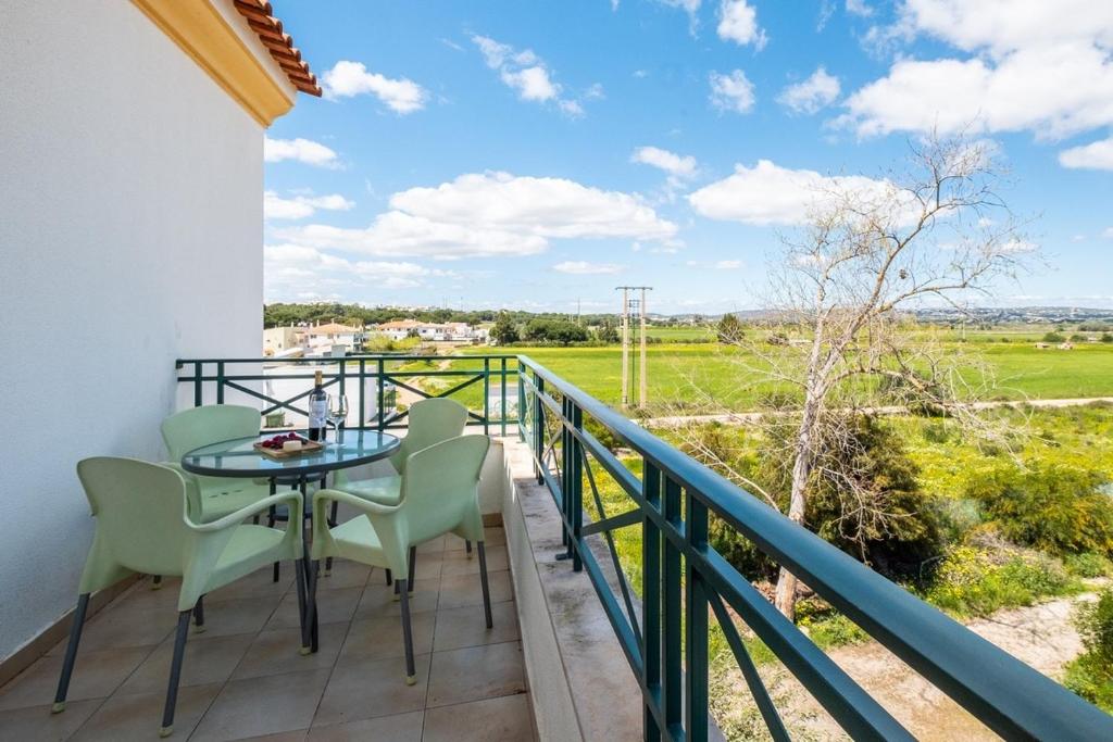 balcone con tavolo, sedie e vista su un campo di Milene Guest House ad Albufeira