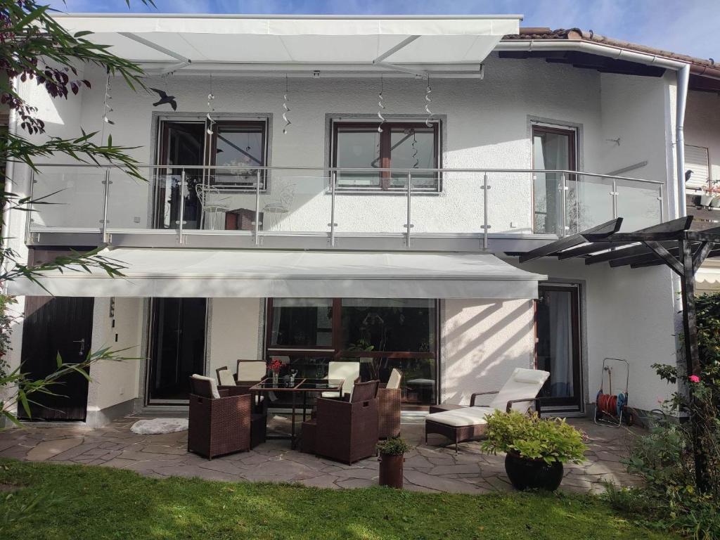 Cette maison blanche dispose d'une terrasse avec des chaises et une table. dans l'établissement Elegant-terraced-house-with-bikes-near-the-lake-children-at-least-6-a-old, à Starnberg