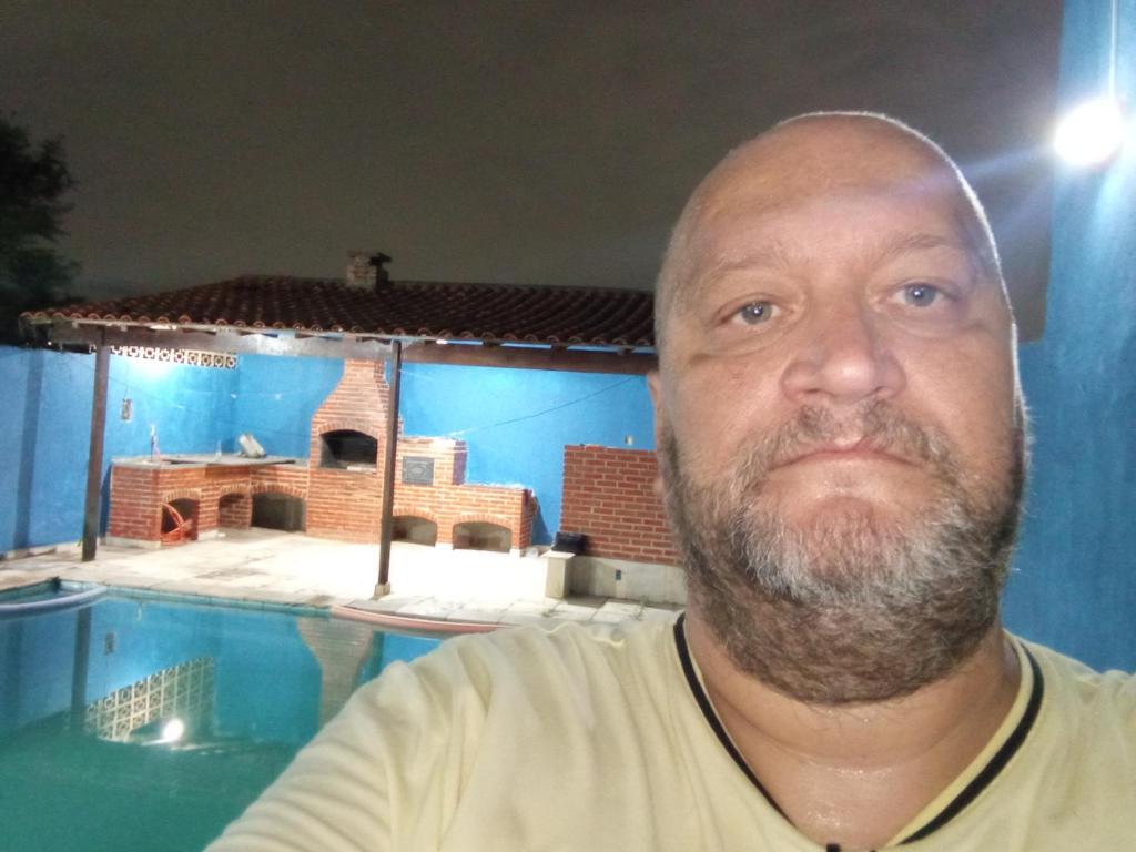 um homem parado em frente a uma piscina em Casa da piscina no Rio de Janeiro